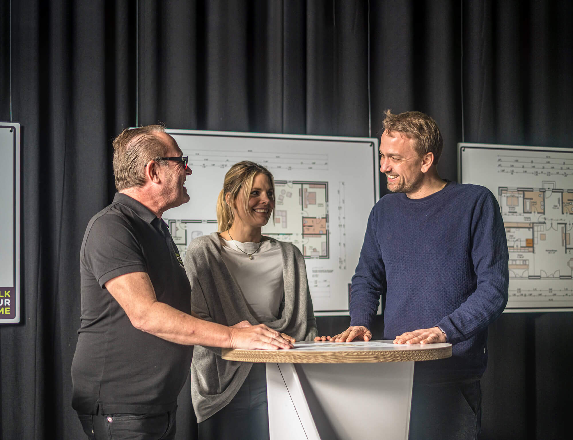 Walk your Home – Mitarbeiter steht mit Kunden am Stehtisch und gibt Antworten auf Fragen